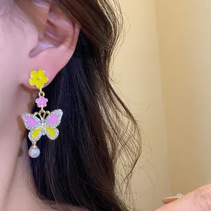 Detailed macro shot of a sweet butterfly drop earring with enamel flowers and a white pearl
