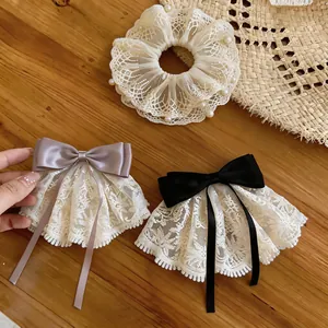 Detailansicht eines Spitzen-Haargummis mit Perlen und Satin-Schleifenclips auf Holz