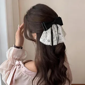 Detailansicht einer eleganten schwarzen Haarschleife mit weißer Spitze und Perlen