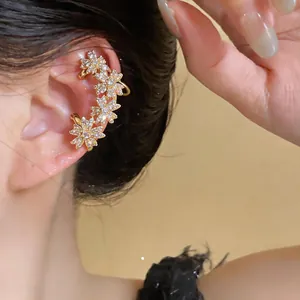 Détails d'un élégant clip d'oreille fleur en or orné de zircons brillants sur l'oreille