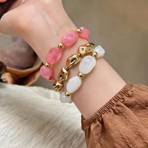 Nahaufnahme von drei unregelmäßigen elastischen Armbändern aus Acryl und Gold am Handgelenk