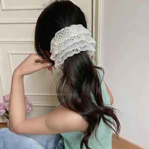 Detailansicht eines eleganten weißen Spitzen-Haargummis mit Perlen auf langem dunklem Haar