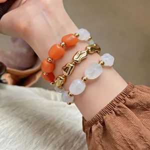 Nahaufnahme von drei unregelmäßigen geometrischen Acrylperlen-Armbändern am Handgelenk
