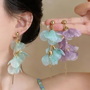 Close-up of summer floral petal long dangle earrings in mint green and purple colors
