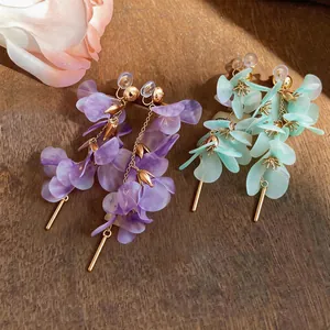 Detailed view of ethereal long floral earrings in purple and mint green petal designs.