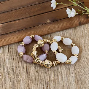 Detailaufnahme von unregelmäßigen Acrylarmbändern mit eleganten, goldfarbenen Metallelementen.