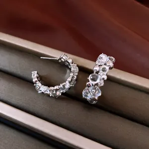 Primo piano professionale di eleganti orecchini a C con pietre chiare brillanti in box
