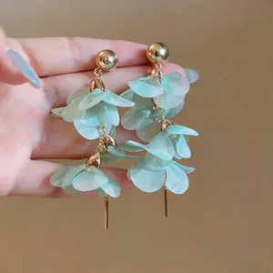Detail view showing the elegant texture of long mint green petal earrings with gold finish.