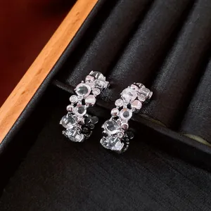 Dettaglio di orecchini a C in argento con zirconi scintillanti e accenti di resina di lusso.