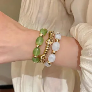 Detailansicht von unregelmäßigen geometrischen Acryl-Armbändern in Grün, Gold und Weiß.