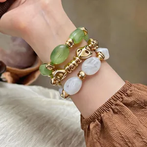 Detailansicht gestapelter unregelmäßiger geometrischer Acryl- und goldfarbener Armbänder