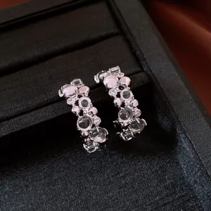 Dettaglio di eleganti orecchini a C in argento con zircone e resina in un portagioie
