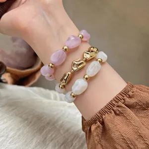 Nahaufnahme von drei gestapelten elastischen Armbändern aus Acryl und Goldperlen