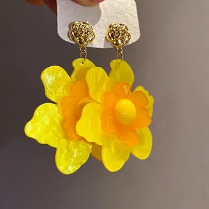 Pendientes colgantes de flores de resina amarilla con tachuelas de rosas doradas.