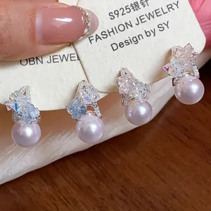Dettaglio di eleganti orecchini a perno con perle rosa, cristalli luccicanti e ago in argento S925