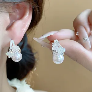 Dettaglio ravvicinato di eleganti orecchini di perle con ago d'argento e cristalli