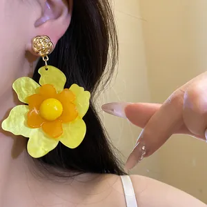 Primer plano de pendientes largos de flor de resina amarilla en una modelo asiática