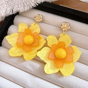 Detalle de pendientes de flores de resina amarilla multicapa con botones de rosa
