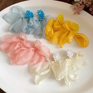 Detailed view of colorful chiffon fabric floral earrings displayed on a white ceramic plate