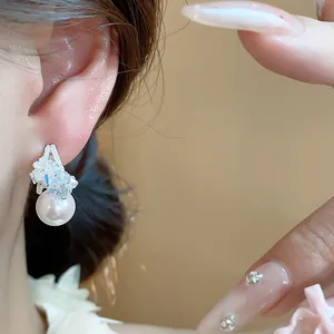 Primo piano di un elegante orecchino a perno in argento a forma di C con pietre e perla