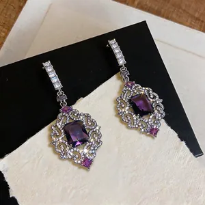 Primer plano de pendientes estilo palacio vintage con piedras púrpuras y circonitas.
