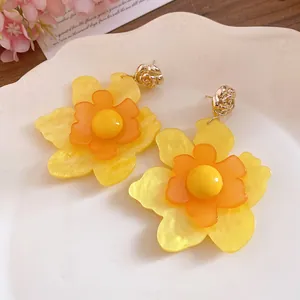 Detalle de pendientes grandes de flores de resina amarilla con pernos de rosa dorada