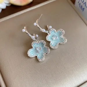 Elegant blue enamel flower earrings with zircon border and pearls on jewelry box.