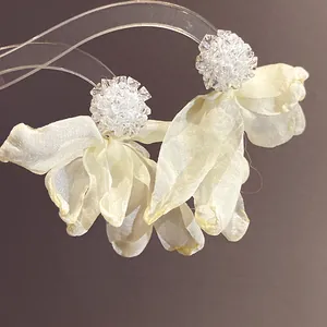 Close-up of elegant chiffon flower earrings with shimmering crystal clusters on top.