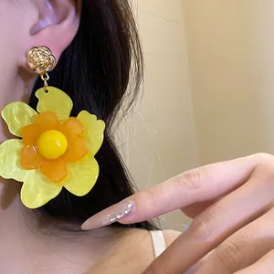 Primer plano detallado de aretes de flor de resina amarilla usados por una modelo.
