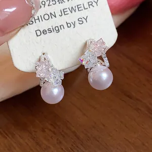 Primo piano dettagliato di eleganti orecchini a C con perla rosa lucida e cristalli.