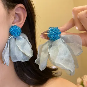 Close-up detail of elegant light blue chiffon flower tassel earrings with blue bead centers