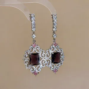 Detalle que muestra pendientes vintage estilo palacio con piedras púrpuras y circonio