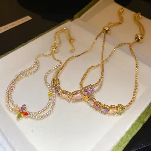 Vue détaillée de bracelets plaqués or 14K avec des breloques fleurs en zircone colorées