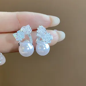 Dettaglio di eleganti orecchini color argento con perle bianche e cristalli scintillanti