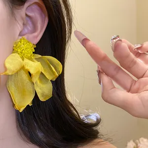Detailed view of large yellow chiffon flower earrings with S925 silver needles worn by model