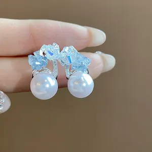 Primo piano di eleganti orecchini a perla a forma di C decorati con cristalli azzurri