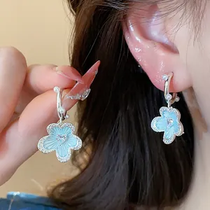 Macro detail of light blue dripping oil flower earrings with zircon hearts and pearls
