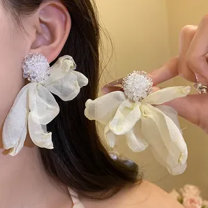 Detailed macro view of white chiffon flower tassel earrings with intricate beadwork
