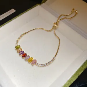 Détail d'un bracelet plaqué or avec des zircons ovales colorés dans un écrin à bijoux.