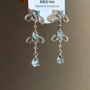 Detail of silver-tone earrings with light blue heart and teardrop stones on a white card