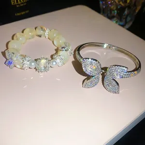 Luxury sparkling zircon butterfly bangle and beaded bracelet set on a soft pink surface