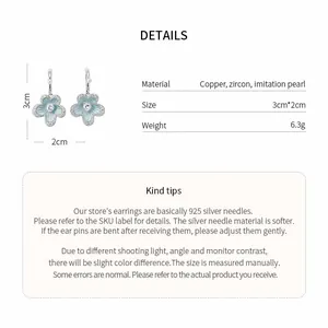 Detailed view of light blue flower stud earrings with pearl center and silver needles.
