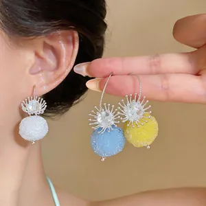 Detailed view of textured round pendant earrings in blue, yellow, and white colors