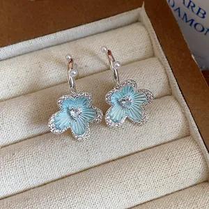 Detailed view of light blue enamel flower earrings with CZ and pearls in a jewelry box