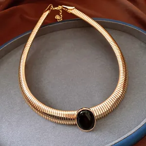 Primo piano di collana vintage dorata a lisca di pesce con cabochon ovale in resina nera.