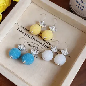 Detailed macro view of round frosted glass earrings in yellow blue and white
