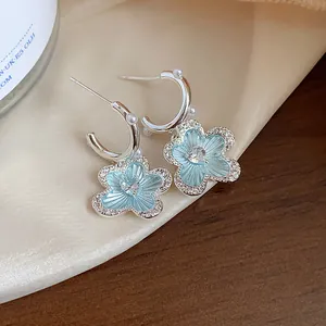 Close-up of blue flower earrings with heart-shaped zircon and pearl accents