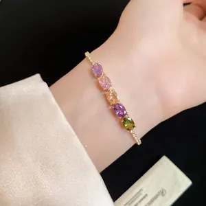Gros plan d'un bracelet plaqué or 14K avec des zircons ovales colorés au poignet.