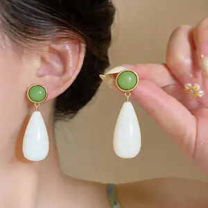 Close-up view of elegant teardrop earrings with green resin stud and white drop