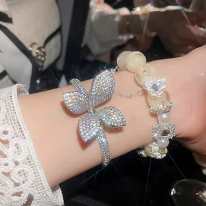 Close-up of sparkling cubic zirconia flower bangle and pearl beaded bracelet set